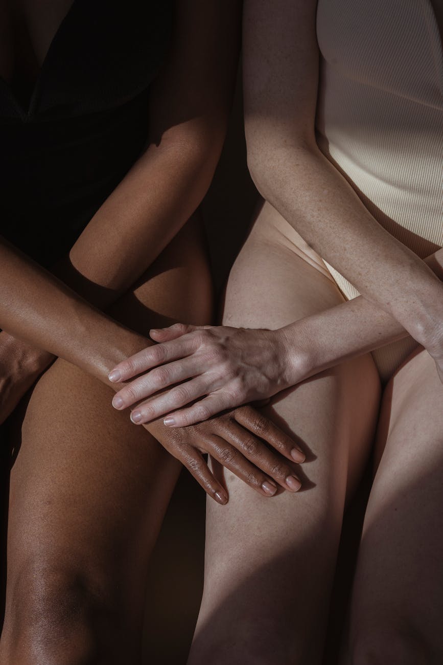 crop diverse females holding hands while sitting together