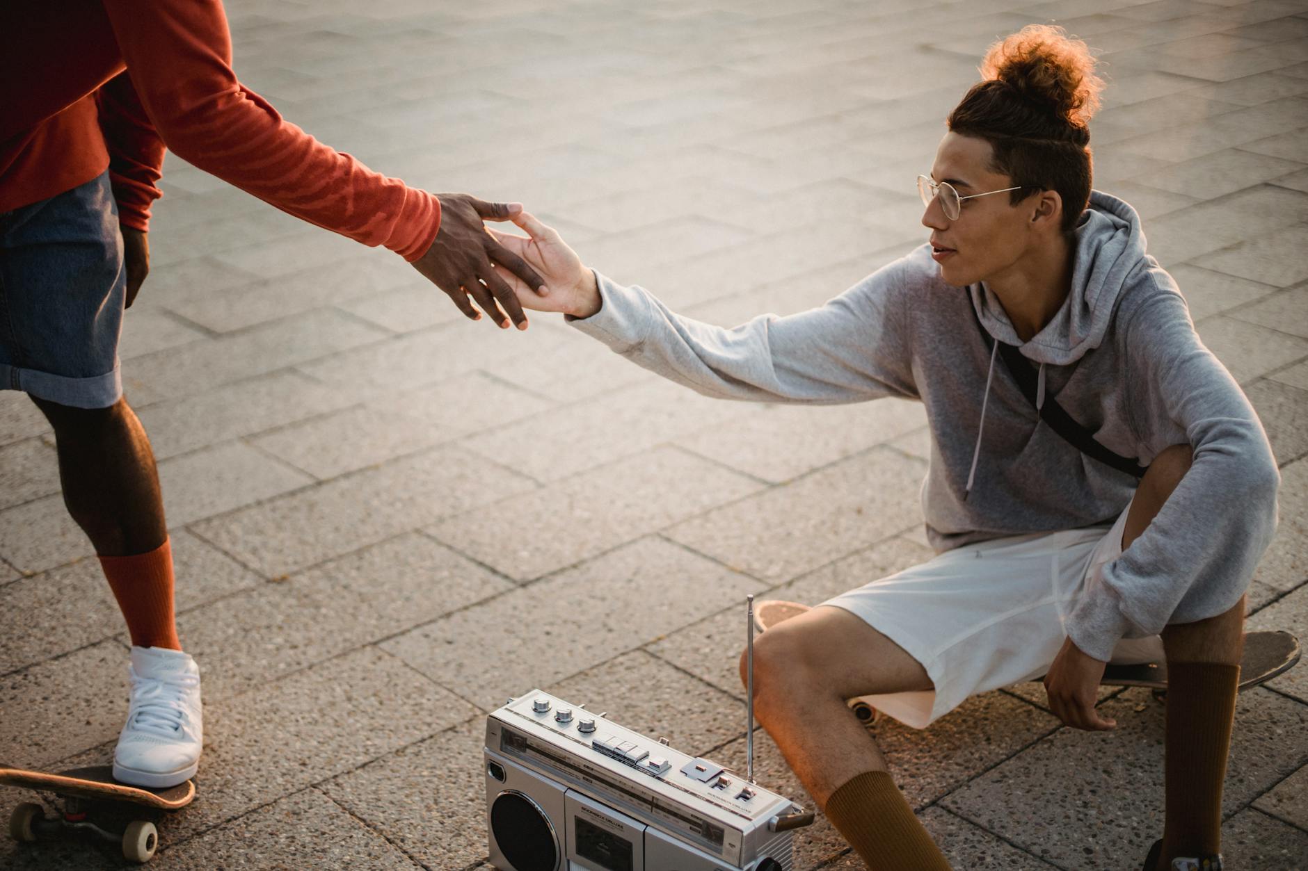 trendy multiracial skaters greeting each other during training on street